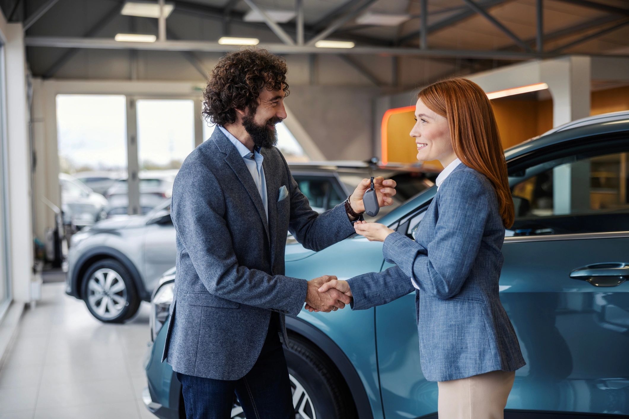 Customer receiving a car key and shaking hands with a salesperson